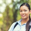 Closeup headshot portrait, happy, young beautiful business woman in blue shirt smiling isolated outdoors background with trees. Positive human emotions, facial expressions